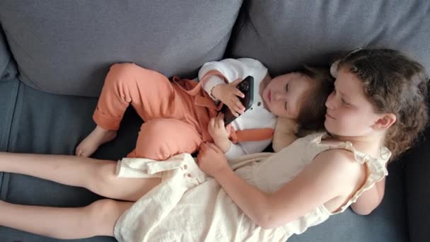 Top View Two Little Sisters Holding Phone Using Smartphone Playing — 图库视频影像