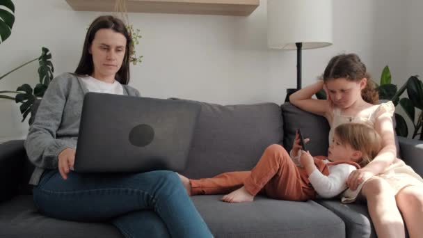 Concentrated Young Mom Daughters Relax Online Using Different Gadgets Sofa — Vídeo de stock