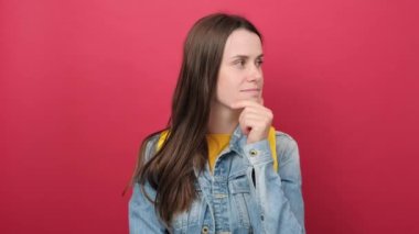 Portrait of shocked young brunette woman student with yellow backpack gaping because have just surprised with gift, posing isolated over red color background wall in studio. Education concept
