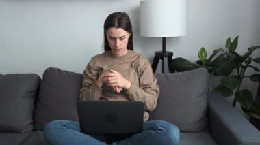 Focused woman sit on sofa in living room put portable computer on laps talking by video conference call app. Job interview process from home, negotiations using modern technology, video call event