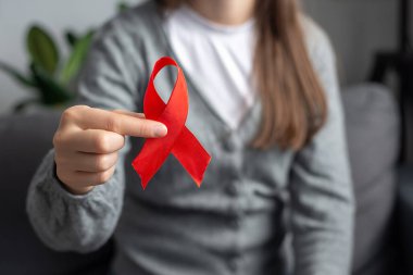 Kadın gönüllü AIDS hastalıklarını bilinçlendirmeye, sağlık hizmetlerine ve tıp konseptine devam ediyor. Kanepede oturan genç bir kadının elinde küçük kırmızı bir göğüs kanseri sembolü var. Hastalıklı insanları destekliyor.