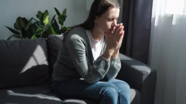 Endişeli genç bir kadın gri koltukta oturmuş elleri bağlı Tanrı 'ya dua ediyor ve hayatı tehlikede. Kafkas kadın 20 'li yaşlarda zihinsel olarak konsantre olmaya çalışıyor. Yüce güçlerden şans diliyor.