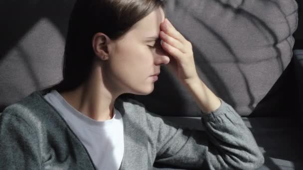 一个心不在焉的黑发女人 远远地凝视着 一个人坐在沙发上 忧心忡忡地沉思着问题 陷入沉思 情绪低落的概念 — 图库视频影像