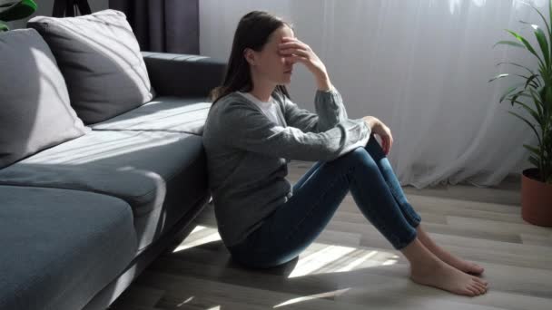 Nieszczęśliwa Młoda Kobieta Myśląca Problemach Siedząca Sama Podłodze Salonie Sfrustrowana — Wideo stockowe