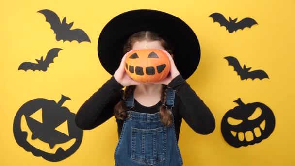 Retrato Niña Sonriente Divertida Sombrero Negro Sosteniendo Pequeña Calabaza Naranja — Vídeo de stock