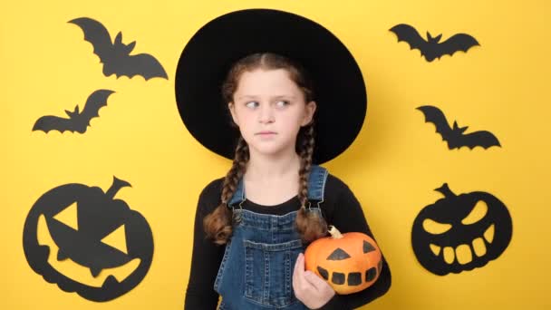 Büyük Siyah Şapkalı Elinde Balkabağı Olan Küçük Eğlenceli Bir Kız — Stok video