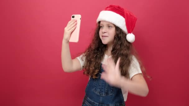 Niña Sonriente Con Sombrero Santa Recibe Videollamada Usando Teléfono Celular — Vídeo de stock