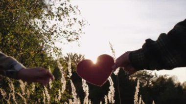 Anne ve kızının arka planda küçük kırmızı kalpler tutarken güzel günbatımında ya da sonbahar günü gün doğumunda büyük çimler ve ormanlar. Kalp, sağlık, aile, aşk bakımı ve ilişki kavramı