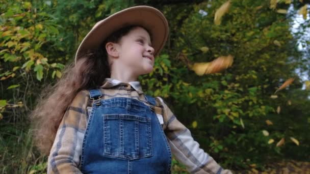 Şapkalı Mutlu Küçük Kızın Portresi Düşen Sonbahar Yapraklarının Keyfini Çıkarır — Stok video