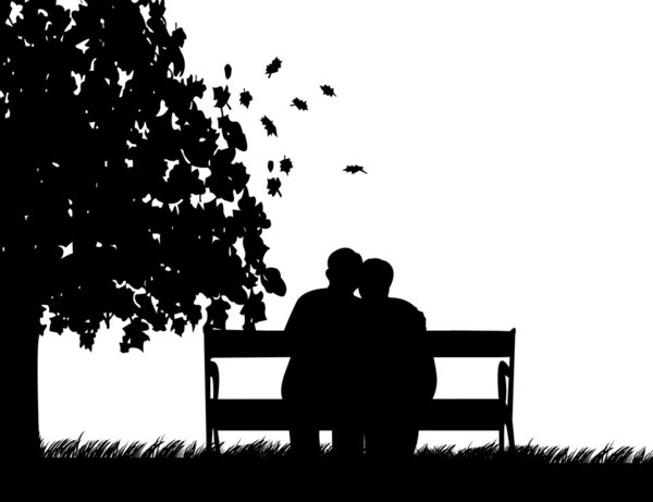 Lovely retired elderly couple sitting on bench in park in autumn or fall