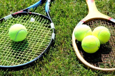 eski ve yeni tenis raketleri, toplarla çim kortta