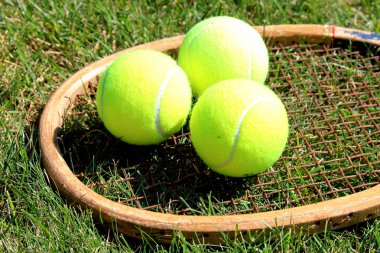 Vintage tennis racket with balls on grass court clipart