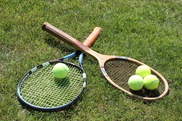 Vintage and new tennis rackets with balls on grass court — Stock Photo, Image