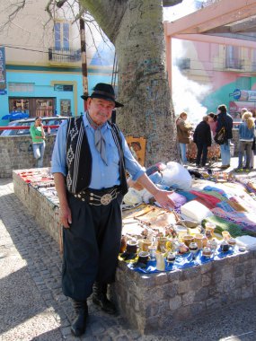 Street vendor dressed as gaucho offers souvenirs in La Boca area of Buenos Aires clipart