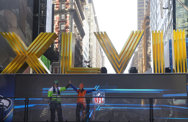 Seattle Seahawlks and Denver Broncos fans posing for picture next to Roman Numerals on Broadway during Super Bowl XLVIII week in Manhattan