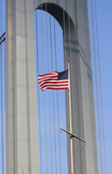 Amerikaanse vlag in de voorkant van verrazano brug in staten island — Stockfoto