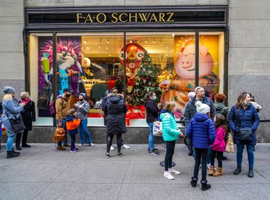 NEW YORK - 5 Aralık 2021: Turistler Manhattan 'ın merkezindeki Rockefeller Plaza' daki FAO Schwarz bayrak gemisi mağazasının önünde soğuk hava mevsiminde uzun kuyrukta kalırlar