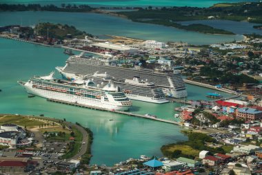 ST. JOHN - ANTIGUA: DECEMBER 30, 2021: A small and a large cruise ship Norwegian Escape, Viking Sea and Grandeur of the Seas docking in the port of St. John's in Antigua and Barbuda (aerial view)