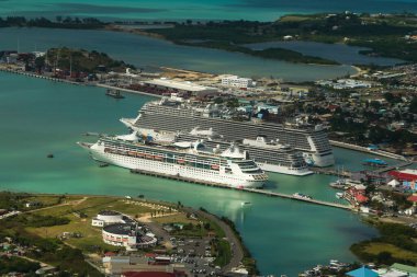 ST. JOHN - ANTIGUA: DECEMBER 30, 2021: A small and a large cruise ship Norwegian Escape, Viking Sea and Grandeur of the Seas docking in the port of St. John's in Antigua and Barbuda (aerial view)