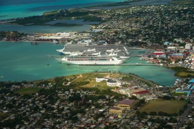 ST. JOHN - ANTIGUA: DECEMBER 30, 2021: A small and a large cruise ship Norwegian Escape, Viking Sea and Grandeur of the Seas docking in the port of St. John's in Antigua and Barbuda (aerial view)