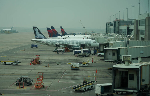 DENVER, COLORADO - AUGUST 7, 2021: Frontier and Delta Airlines planes on tarmac at Denver International Airport covered by smoke. 