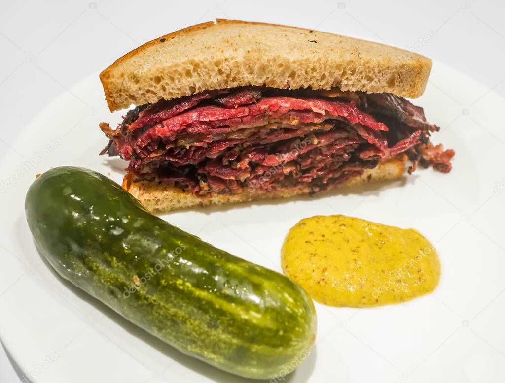 Famous Pastrami sandwich with pickle and mustard served in New York Deli