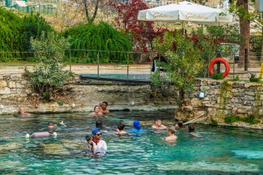 PAMUKALE, TURKEY - 1 Kasım 2021: Pamukkale, Türkiye 'de antik havuzun (Kleopatra Hamamı) tadını çıkaran turistler