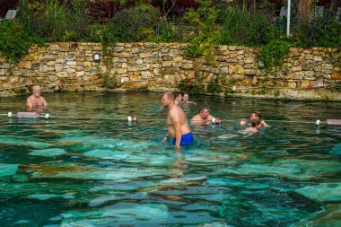 PAMUKALE, TURKEY - 1 Kasım 2021: Pamukkale, Türkiye 'de antik havuzun (Kleopatra Hamamı) tadını çıkaran turistler