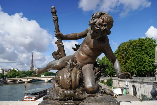 Statue of cupid on the Pont Alexandre III with Eiffel tower in background in a beautiful summer day in Paris, France