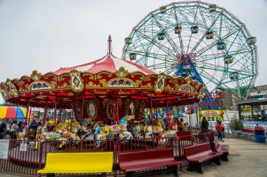 BROOKLYN, NEW YORK - MAY 9, 2021: Coney Island carousel and Wonder Wheel at the Coney Island amusement park. Deno's Wonder Wheel is a hundred and fifty foot eccentric Ferris wheel built in 1920
