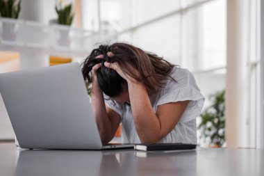 Bunalımlı, uzaktan kumandalı, üzgün bir kadın bilgisayarın önünde hayal kırıklığına uğramış bir şekilde oturuyor. Ya da çalışma masasının üstünde, pencereleri pencereli, modern, aydınlık oturma odasındaki çalışma masasında.