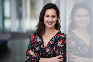 Çekici, kahverengi saçlı bir kadın, beyaz bir arka planda, modern bir üniversite lobisinde günlük tutuyor.