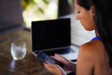 Uzaktan kumandalı bronzlaşmış bir koçun arka planı boş bir dizüstü bilgisayara ya da tropikal bir tatil ortamındaki defter ekranına bakıyor.