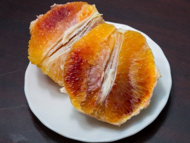 Soyulmuş ve dilimlenmiş portakallı bir tabak. Taze kanlı meyve..