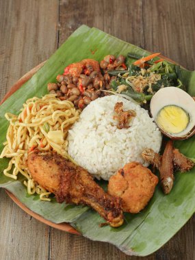 Geleneksel öğle yemeği, yumurta ve sebzeli pilav ve muz yapraklarıyla kaplı ahşap bir tabakta servis edilen kızarmış tavuk.
