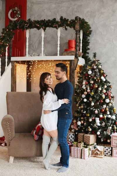 새해 휴가를 위해 장식 한 거실에서 크리스마스 트리 근처에 포즈를 취하고 있는 행복 한 커플들 — 스톡 사진