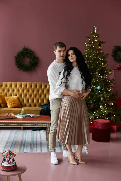 Jeune homme étreint sa charmante petite amie à l'intérieur de la maison décoré pour la fête du Nouvel An — Photo