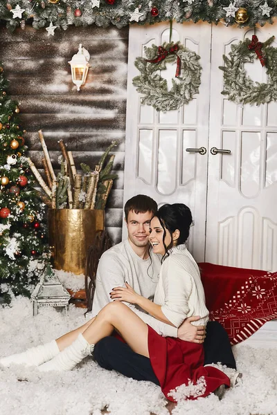 Красивый молодой человек и красивая модель девушка сидят на лестнице в зимний экстерьер загородного дома с рождественскими украшениями в деревенском стиле — стоковое фото