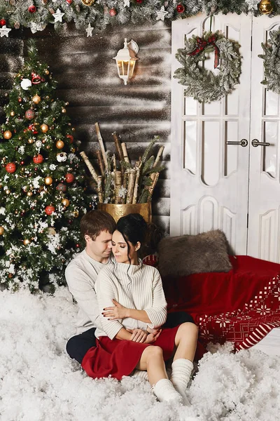 Beau jeune homme et belle fille modèle assis sur les escaliers à l'extérieur d'hiver d'une maison de campagne avec des décorations de Noël dans un style rustique — Photo