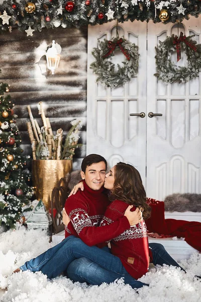Милая пара влюбленных в рождественской одежде, позирующих в рождественском украшенном интерьере — стоковое фото