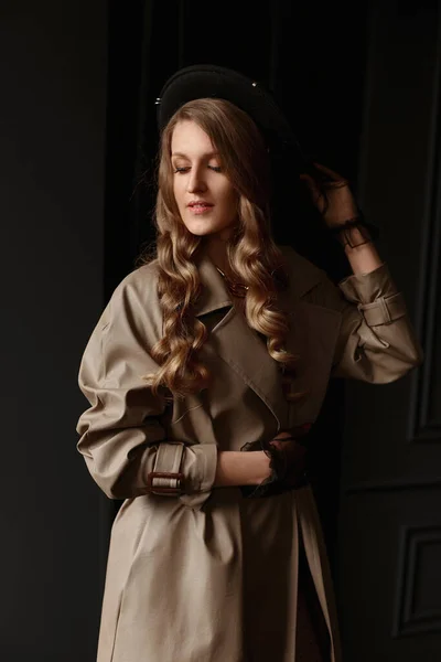En ung elegant kvinna i beige trenchcoat och trendig svart hatt. Höst eller vår mode reklam koncept — Stockfoto