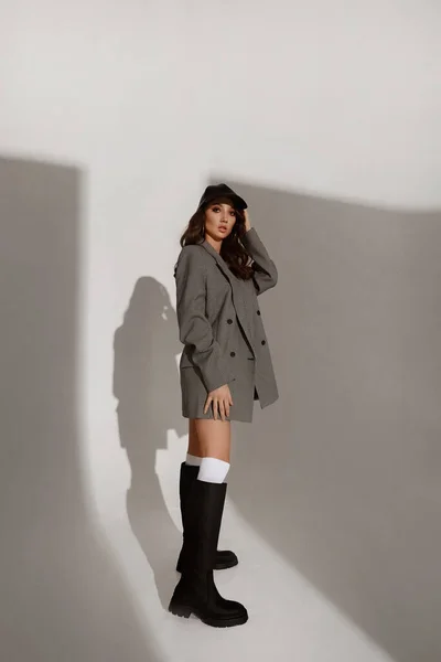 Beyaz arka planda şık botları ve şık ceketi olan genç bir kız model. — Stok fotoğraf
