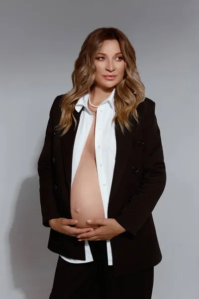 Prachtige jonge zwangere vrouw in zwart pak met blote buik — Stockfoto