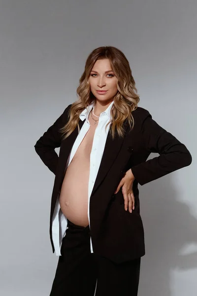 Wunderschöne junge schwangere Frau im schwarzen Anzug mit nacktem Bauch — Stockfoto