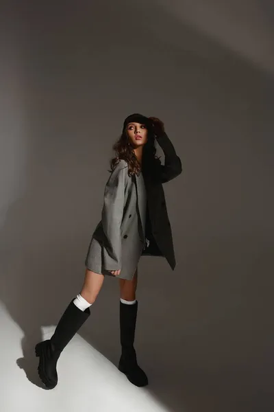 Mode modell flicka i en fashionabel överdimensionerad blazer, BH och fashionabla stövlar över grå bakgrund — Stockfoto