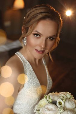 Şık bir gelinlik giymiş, güzel bir kuaförü ve mükemmel bir düğün makyajı olan muhteşem bir kadın.