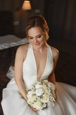 Gelinlikli genç kadın yaz günü çayırda poz veriyor.