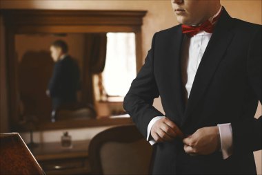 Zarif yakışıklı bir işadamının kesilmiş portresi mi yoksa smokinini düzelten kırmızı papyonlu şık bir damat mı?