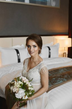 Harika vücutlu, dantel iç çamaşırlı, beyaz şeffaf gecelikli, yatağında çiçeklerle poz veren çekici bir manken kız.