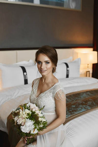 Harika vücutlu, dantel iç çamaşırlı, beyaz şeffaf gecelikli, yatağında çiçeklerle poz veren çekici bir manken kız.